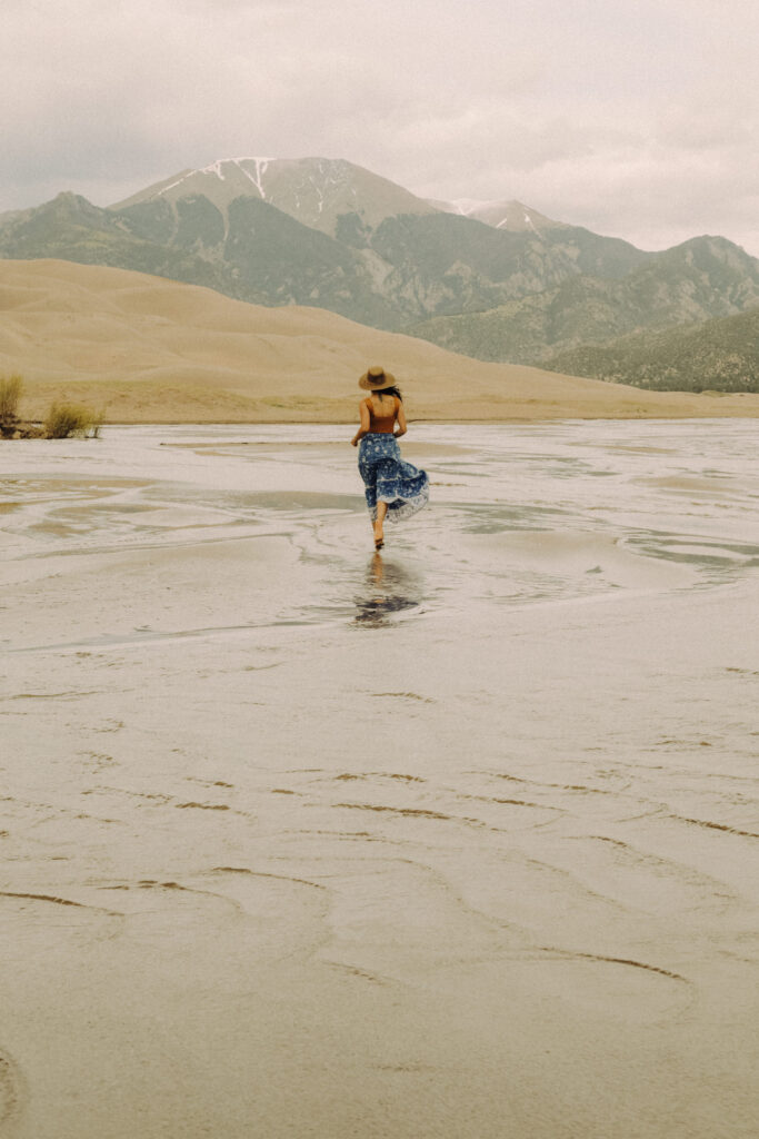 A girl named Jessy running along the river by Great Sand Dunes National Park